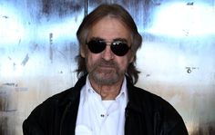 an older man wearing sunglasses standing in front of a metal wall