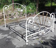 a white metal bed frame sitting on top of a parking lot