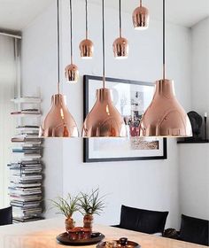 a dining room table with some lights hanging over it