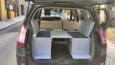 the back end of a small car with its trunk open and two benches in it