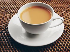 a cup of coffee sitting on top of a saucer next to a wicker table