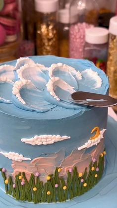 a blue cake decorated with flowers and clouds