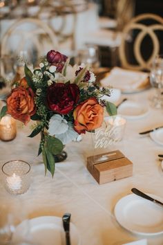 a centerpiece with flowers and candles on a white table cloth at a wedding reception