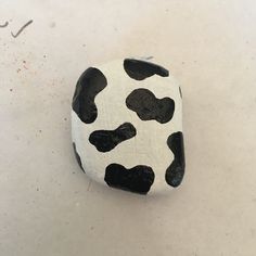 a black and white cow print rock sitting on top of a table next to a marker