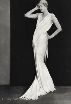 an old photo of a woman in a white dress with her hands on her head