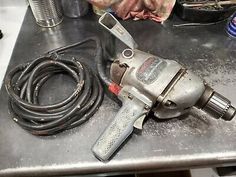 a drill is sitting on top of a table next to a hose and other tools