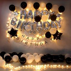 a birthday party with black and white balloons, lights and streamers on the wall