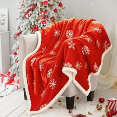 a red and white blanket sitting on top of a chair next to a christmas tree