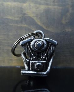 a metal keychain with a motorcycle engine on it's front end, sitting on top of a wooden surface