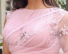 a woman in a pink sari with flowers on her chest and arms, smiling at the camera