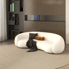 a white couch sitting on top of a rug next to a book shelf filled with books