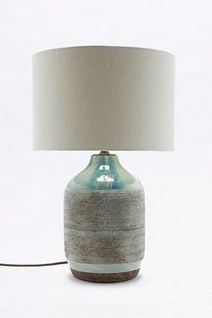 a table lamp with a blue and white vase on it next to a light bulb