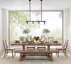 a dining room table and chairs with candles on them in front of a large window