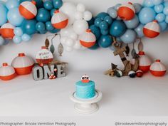 a blue cake sitting on top of a white plate next to balloons and other decorations