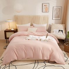 a bed with pink sheets and pillows in a bedroom