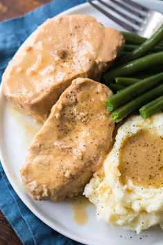 mashed potatoes, green beans and gravy on a white plate with a fork