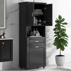 a bathroom with a black cabinet and sink next to a potted plant on the floor