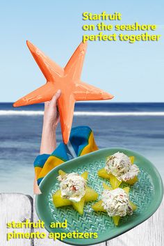 a person holding up a starfish on the beach with food in front of them