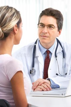 a doctor talking to a woman in front of a laptop computer