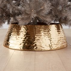 a christmas tree in a gold pot with silver ornaments on it's top and bottom