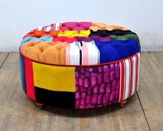 a multicolored round ottoman sitting on top of a wooden floor