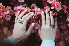 two hands touching each other with pink flowers in the background