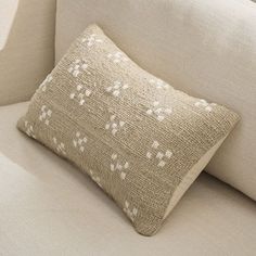 a close up of a pillow on a couch with a white and beige pattern behind it