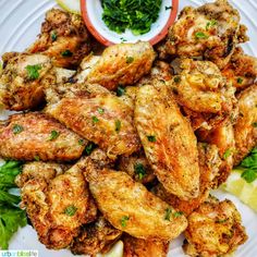 chicken wings with parsley and lemon wedges on a white plate, ready to be eaten