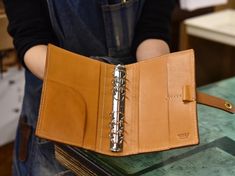 a person holding an open wallet with a pen in it's pocket on top of a table