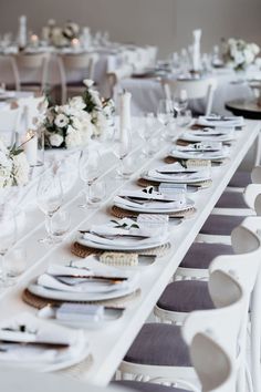 the table is set with white flowers and place settings for an elegant dinner or reception