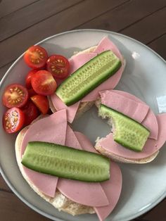 a sandwich with cucumber and tomato slices on it sitting on a white plate