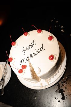 a white cake sitting on top of a wooden table next to a fork and knife