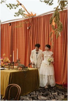 a couple standing next to each other in front of a table