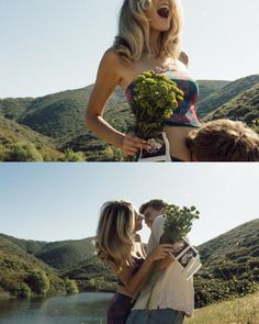 two people kissing each other in front of a lake and mountains, with one person holding flowers