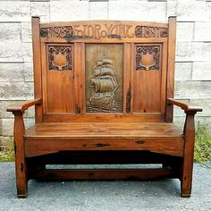 an old wooden bench with carvings on the back and sides, sitting in front of a brick wall