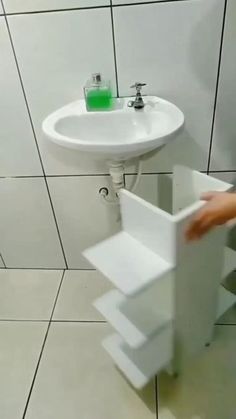 a bathroom with a sink, toilet and hand held over the wall by a towel dispenser