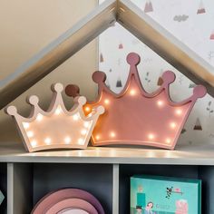 a pink princess crown sits on top of a book shelf next to a plate and other items