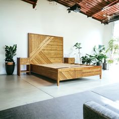 a bed sitting in the middle of a room next to a couch and potted plants