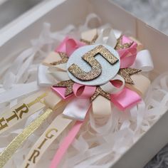 a pink and gold bow with the letter j on it in a box that says happy birthday