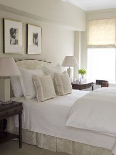 a bed with white linens and pillows in a bedroom next to a lamp on a table