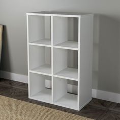 a white book shelf sitting on top of a carpeted floor next to a painting