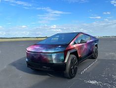 an electric car with colorful paint on it's body parked in a parking lot