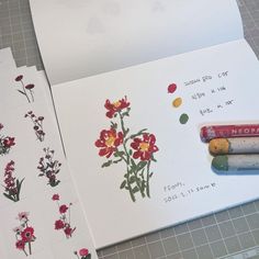 some flowers are drawn on white paper with crayons and pencils next to them