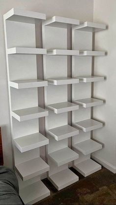 a white book shelf sitting in the corner of a room next to a wall with shelves on it