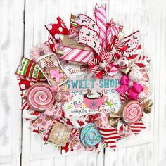 a wreath made out of candy canes and ribbons on a white wooden background with the words sweet shop