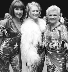 three women dressed in disco costumes posing for the camera