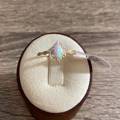 an opal and diamond ring sits in a wooden box on top of a table