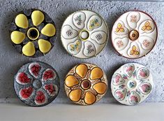 five decorative plates are lined up on the wall, each with different designs and colors