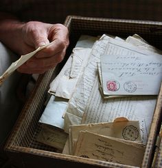 an old man holding a pair of scissors in a box filled with letters and envelopes