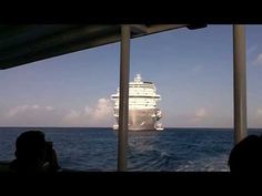 a cruise ship is in the distance as people look out from a boat on the water